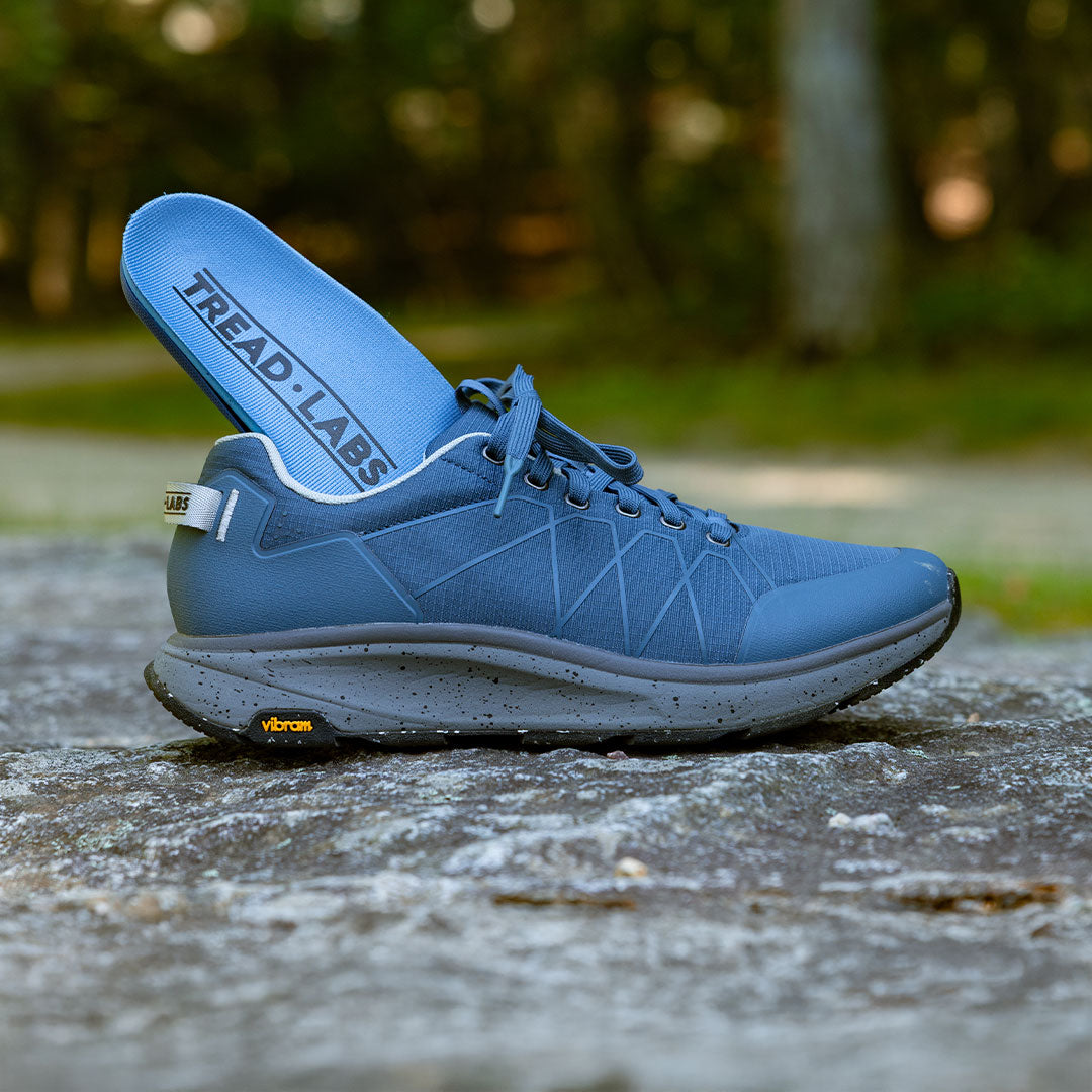Blue athletic shoe with 'Tread Labs' branding on a natural background