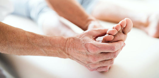 Hands holding a foot on a bed.