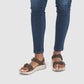 Female model wearing Salinas Leather Sandals in Havana with blue jeans on a white background