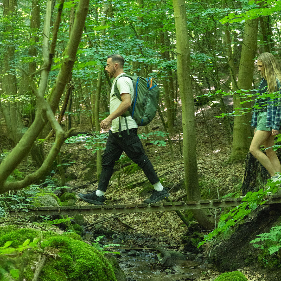 Two people crossing a wooden bridge in a forest